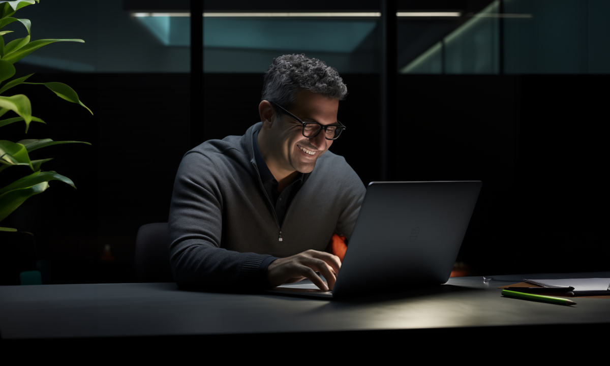 Glimlachende man terwijl hij naar een laptop kijkt als onderdeel van een artikel over wat de beste factureringssoftware is.